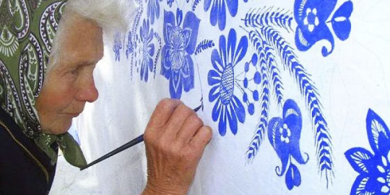 Бабушка рисует узоры на домах